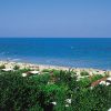 Una spiaggia sabbiosa vista dall'alto con un mare blu e una vegetazione verde.