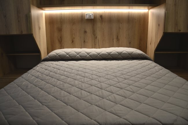 Letto matrimoniale con coperta trapuntata.