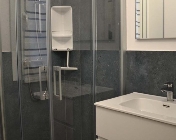Lavabo bianco accanto a una doccia con porta in vetro.