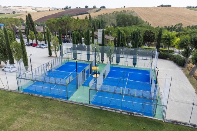 Due campi da padel blu, recintati, in un'area esterna.