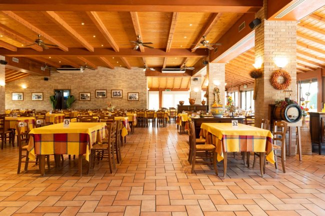 Ampio ristorante con tavoli apparecchiati e sedie.