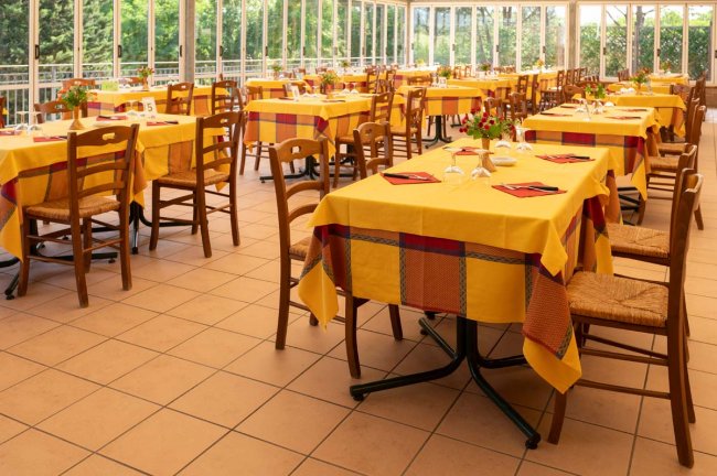 Sala da pranzo luminosa con tavoli apparecchiati.