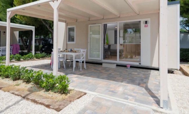 Veranda pavimentata con tavolo e sedie bianche.