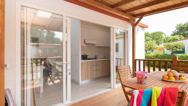 Terrazza con tavolo apparecchiato, cucina visibile.