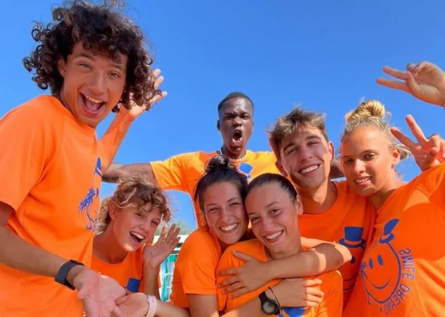 Gruppo di persone sorridenti in magliette arancioni.