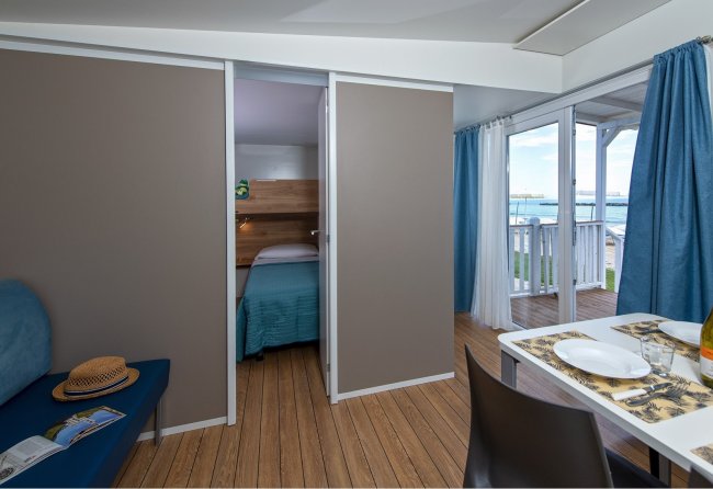 Interno di un bungalow con camera da letto e vista mare.