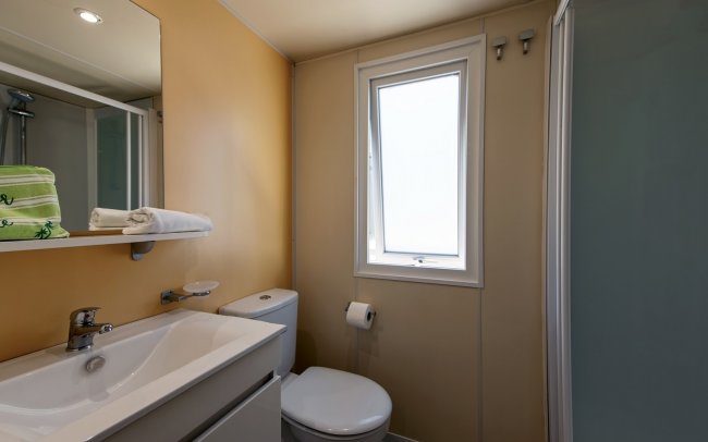 Bagno con finestra, lavabo e doccia discreta.