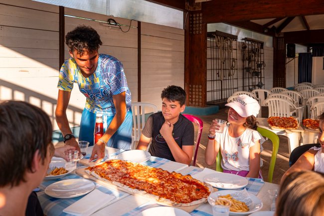 Persona serve pizza a bambini seduti.