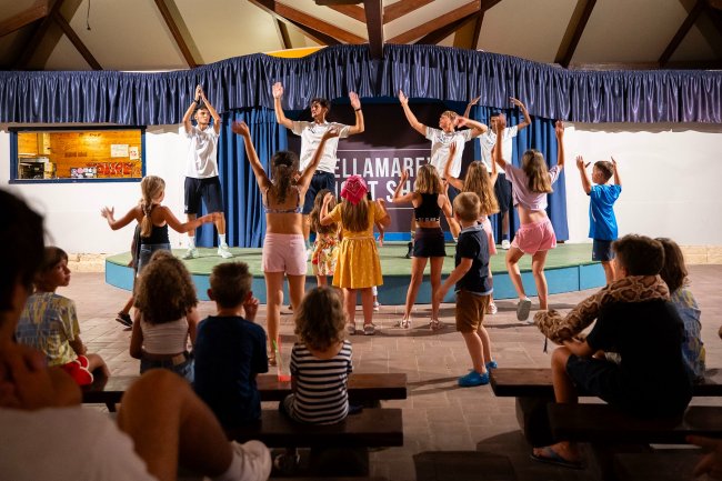 Bambini ballano sul palco con animatori.