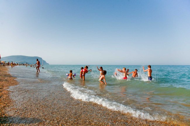 Bambini giocano in acqua lungo la riva.
