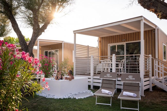 Due persone in vasca esterna con bungalow sullo sfondo.