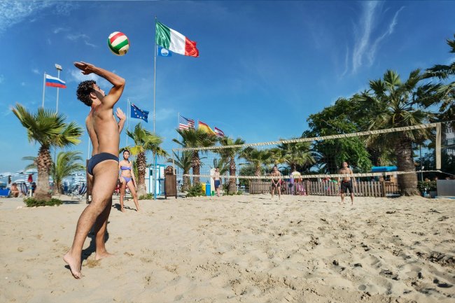 Persone che giocano a beach volley su una spiaggia.