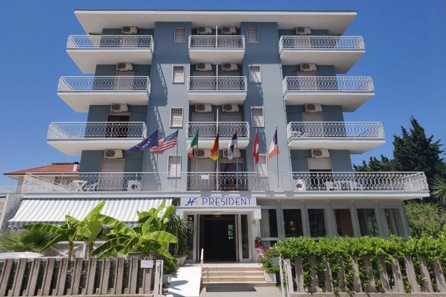 Facciata di un hotel con balconi e bandiere.