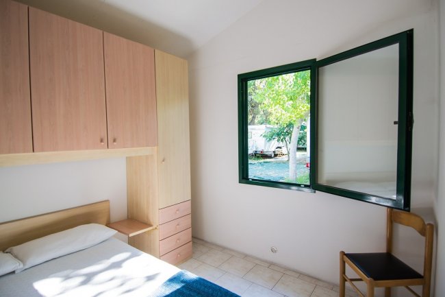 Camera con letto, armadio e finestra aperta.