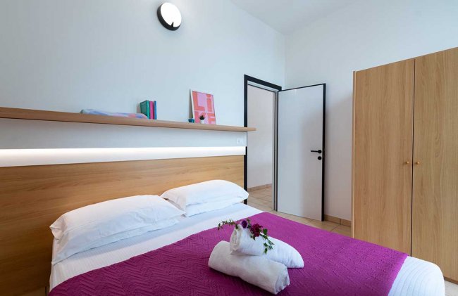 Camera da letto moderna con copriletto viola.