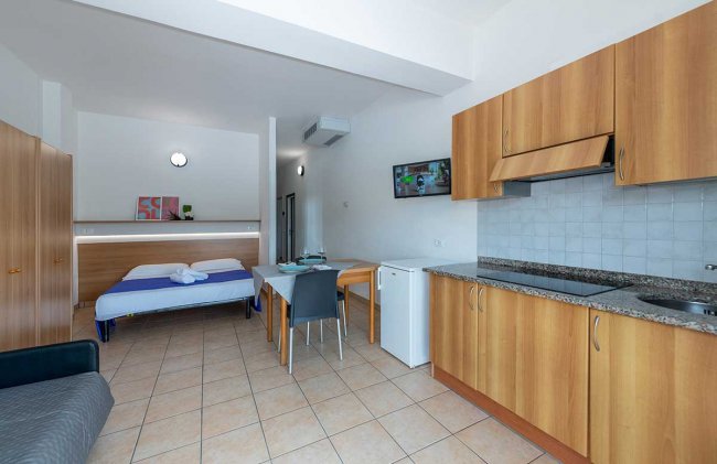 Monolocale con cucina, tavolo e letto blu.