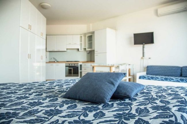 Interno moderno con letto, cucina e TV.