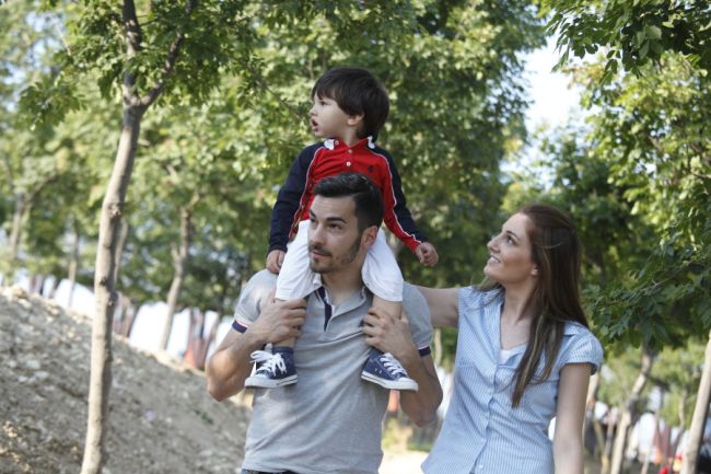 Famiglia che passeggia in un parco verde.