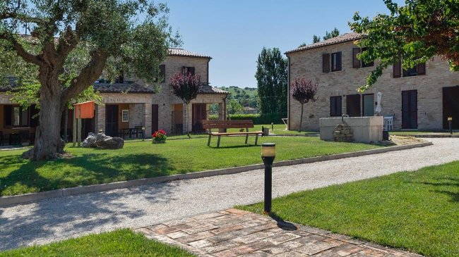 Giardino con alberi e vialetti tra edifici.