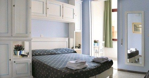 Camera da letto con mobili bianchi, letto matrimoniale e asciugamani piegati.